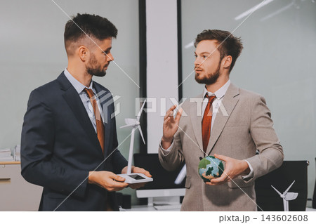 Team presenting a solar and wind energy project with model house, earth globe and green ideas in an office meeting Team presenting a solar and wind energy project with model house, earth globe and green ideas in an office meeting 143602608