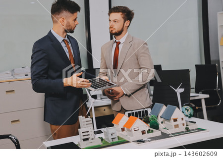 Team presenting a solar and wind energy project with model house, earth globe and green ideas in an office meeting Team presenting a solar and wind energy project with model house, earth globe and green ideas in an office meeting 143602609