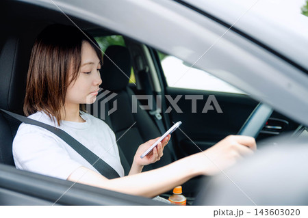 運転席でスマホを操作する若い女性 運転席でスマホを操作する若い女性 143603020