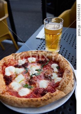 Delicious Neapolitan Pizza and Cold Beer on a Sunny Outdoor Terrace Table Delicious Neapolitan Pizza and Cold Beer on a Sunny Outdoor Terrace Table 143603235