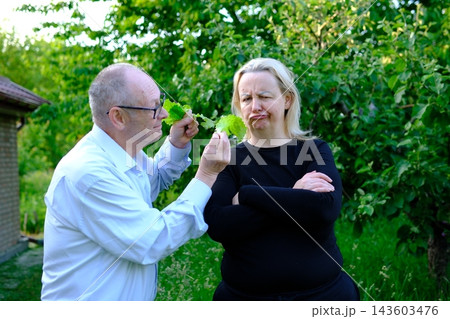 Senior father offering fresh lettuce from garden to adult daughter while encouraging healthy eating in countryside yard Senior father offering fresh lettuce from garden to adult daughter while encouraging healthy eating in countryside yard 143603476