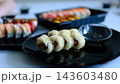 Assorted sushi platter with various types of nigiri, maki rolls, and sashimi on black plate, showcasing Japanese cuisine. Authentic Japanese Food and Culinary Arts. 143603480