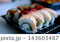 Fresh shrimp and eel sushi rolls with sesame and unagi sauce arranged in black takeaway container for Japanese food delivery 143603487
