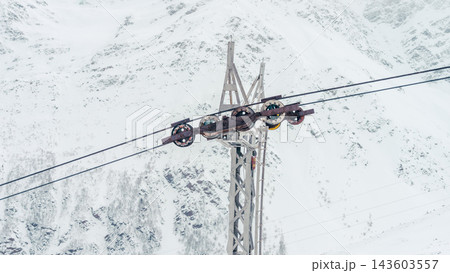 Rusted cable car pulley assembly on steel tower with snowy Caucasus mountain backdrop 143603557