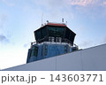 Airport control tower with panoramic windows, antennas, and communication equipment against a cloudy blue sky at Madeira Airport in Portugal. 143603771
