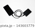 Smartphone connected to a portable power bank with a charging cable on a white background, illustrating mobile charging and backup energy. 143603779