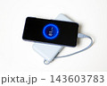 Smartphone charging from a portable light blue power bank with illuminated battery percentage display and cable on a clean white background. 143603783