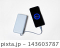 Smartphone charging from a portable light blue power bank with illuminated battery percentage display and cable on a clean white background. 143603787