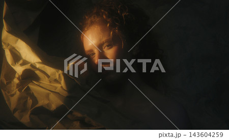 Woman With Hidden Identity Partially Concealed Behind Paper and Dramatic Shadows Woman With Hidden Identity Partially Concealed Behind Paper and Dramatic Shadows 143604259