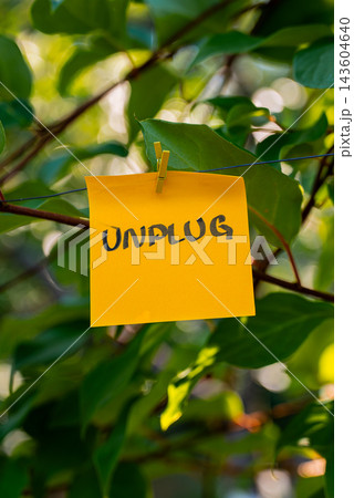Paper note with UNPLUG message against green leafy background. Suitable for digital detox, screen-free lifestyle technology break mindfulness. Paper note with UNPLUG message against green leafy background. Suitable for digital detox, screen-free lifestyle technology break mindfulness. 143604640