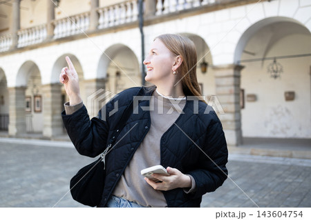 Smiling young woman pointing finger away in European city 143604754