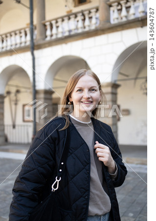 Smiling young woman standing in front of historic European building Smiling young woman standing in front of historic European building 143604787