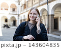 Smiling young woman talking on smartphone in old European city 143604835