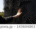 Person hand pressing on a large outdoor pin art installation 143604863