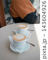 Two cups of hot cappuccino with latte art on a table in a cafe 143604926