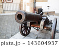 Ancient iron cannon on wooden wheels in a castle courtyard 143604937