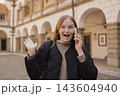 Shocked young woman talking on smartphone in European city 143604940
