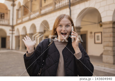 Shocked young woman talking on smartphone in European city Shocked young woman talking on smartphone in European city 143604940