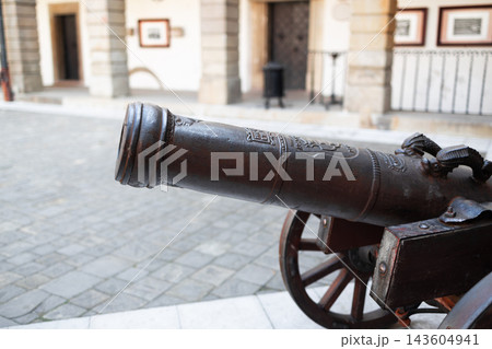 Ancient iron cannon on wooden wheels in a castle courtyard Ancient iron cannon on wooden wheels in a castle courtyard 143604941