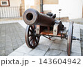 Ancient iron cannon on wooden wheels in a castle courtyard 143604942
