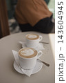 Two cups of hot cappuccino with latte art on a table in a cafe 143604945