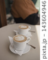 Two cups of hot cappuccino with latte art on a table in a cafe 143604946