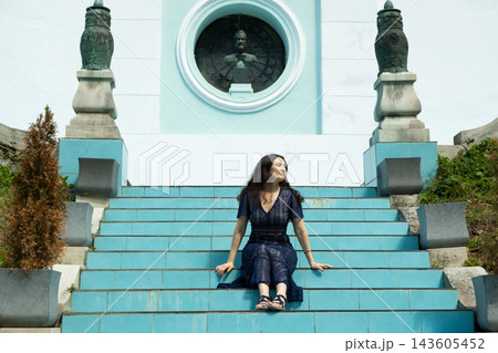 Confident woman sitting on stairs posing with elegance and feminine grace outdoors 143605452