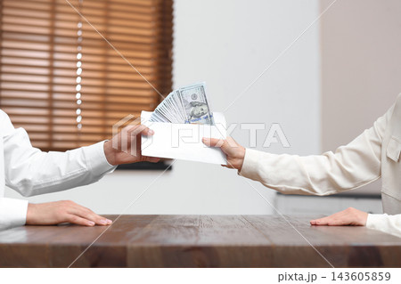 Woman giving bribe money to man at table indoors, closeup 143605859