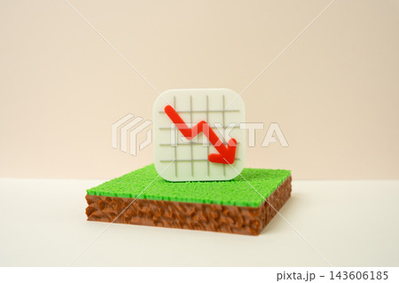 A plot of land and a falling arrow chart. Symbol of land investment risk and loss today. Falling demand. Concept of declining property value and real estate market crisis. A plot of land and a falling arrow chart. Symbol of land investment risk and loss today. Falling demand. Concept of declining property value and real estate market crisis. 143606185