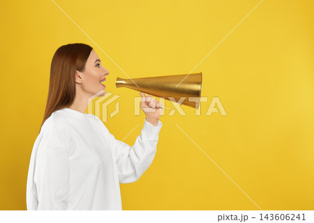 Young woman with vintage megaphone on yellow background 143606241