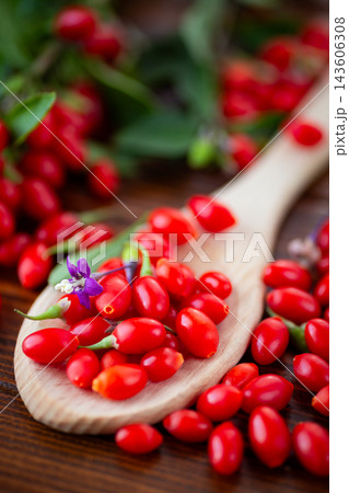 Fresh red goji berries with foliage on natural wooden background 143606308