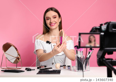 Beauty blogger recording makeup tutorial on pink background Beauty blogger recording makeup tutorial on pink background 143607340
