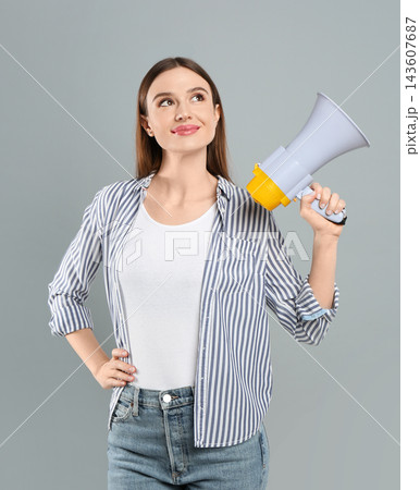 Young woman with megaphone on light grey background Young woman with megaphone on light grey background 143607687