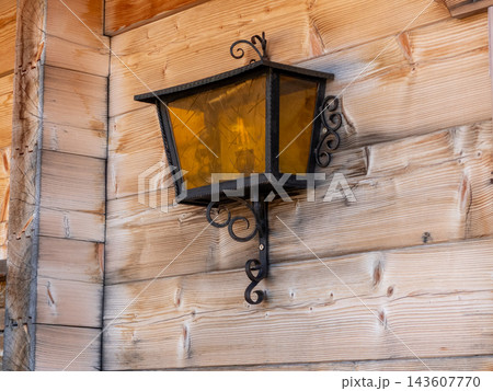 Vintage wrought iron lantern decorating rustic wooden wall Vintage wrought iron lantern decorating rustic wooden wall 143607770