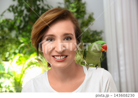 Happy woman with Alexandrine parakeet on blurred background 143608230