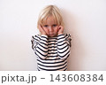 Naughty Little Blonde Girl Covering Ears and Making a Face 143608384