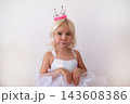 Hopeful Little Blonde Girl Holding Clasped Hands and Pleading  143608386