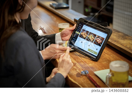 居酒屋のカウンター席でタブレットオーダーする客の手元 143608882