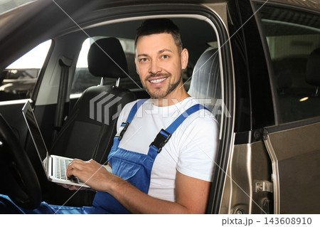 Mechanic with laptop doing car diagnostic at automobile repair shop Mechanic with laptop doing car diagnostic at automobile repair shop 143608910