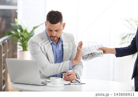 Businessman refusing to take bribe at table indoors Businessman refusing to take bribe at table indoors 143608911