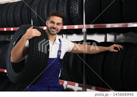 Male mechanic with car tire in auto store Male mechanic with car tire in auto store 143608948