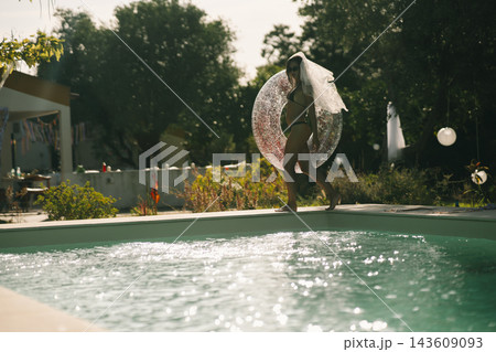 Bride holding a transparent pool ring beside a garden swimming pool Bride holding a transparent pool ring beside a garden swimming pool 143609093