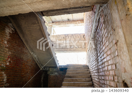Unfinished concrete stairwell with exposed brick walls and daylight inside a building under renovation. Stairwell safety assessment construction renovation and structural inspection Unfinished concrete stairwell with exposed brick walls and daylight inside a building under renovation. Stairwell safety assessment construction renovation and structural inspection 143609340