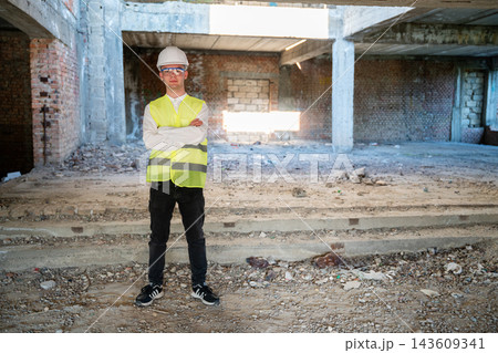 Construction inspector in safety vest and hard hat standing inside an unfinished building. Building condition assessment and pre renovation property inspection Construction inspector in safety vest and hard hat standing inside an unfinished building. Building condition assessment and pre renovation property inspection 143609341
