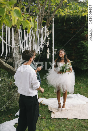 Bride Smiling Toward Groom Under White Ribbons 143609497