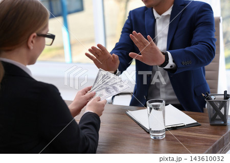 Businessman refuses to take bribe money at wooden table, closeup Businessman refuses to take bribe money at wooden table, closeup 143610032