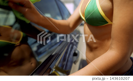 Woman washing a car in a bikini outdoors 143610207