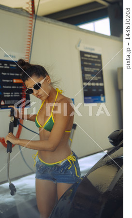 Young woman washing car at self service wash Young woman washing car at self service wash 143610208