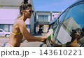 Young woman washing a car outdoors on a sunny day 143610221
