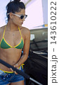 Young woman in sunglasses standing beside car 143610222